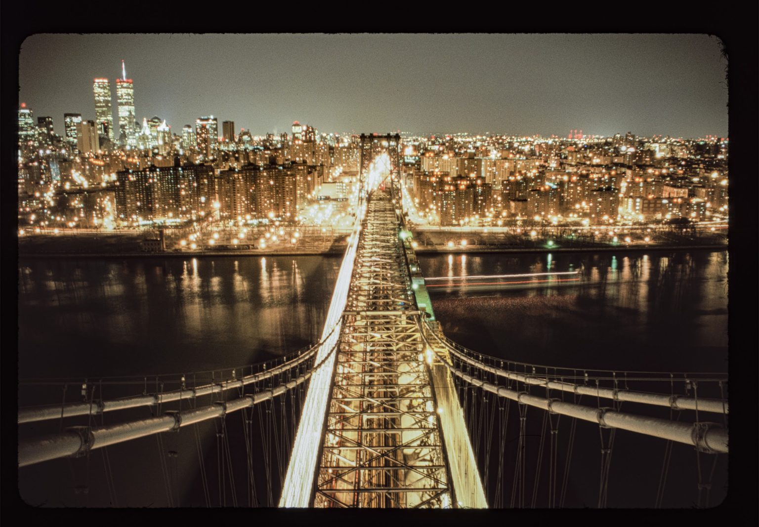 Manhattan at night in the year 2000, seen from the Williamsburg Bridge looking along its lit span towards the skyline